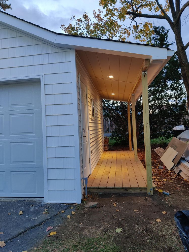A white garage with a porch attached to it.
