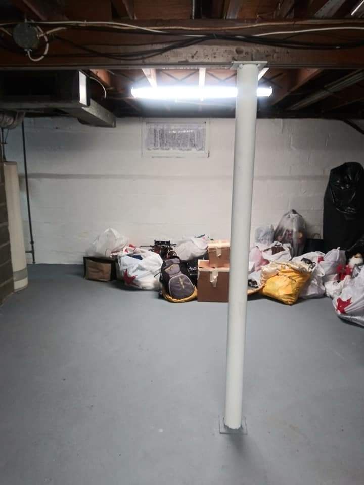 A basement filled with boxes and bags and a white pole