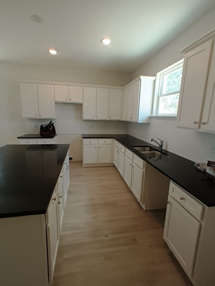 A kitchen with white cabinets and black counter tops