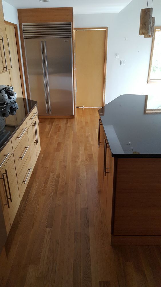 A kitchen with hardwood floors, stainless steel appliances, and a black counter top