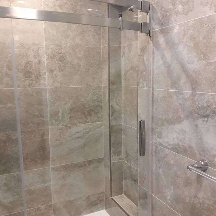 A bathroom with a sliding glass shower door and tiled walls