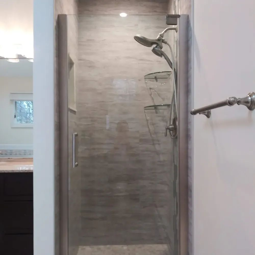 A bathroom with a walk in shower with a glass door and a shower head