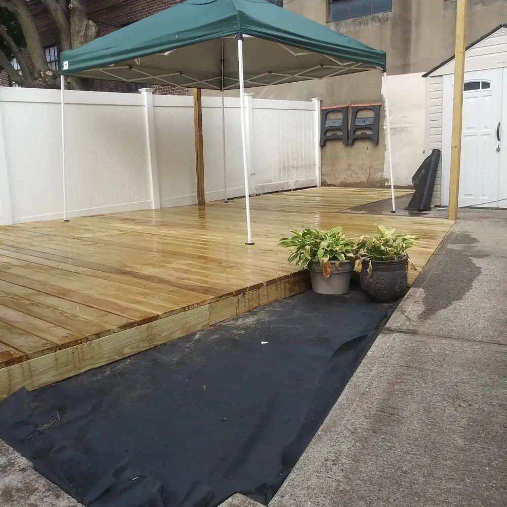 A wooden deck with a green canopy and potted plants