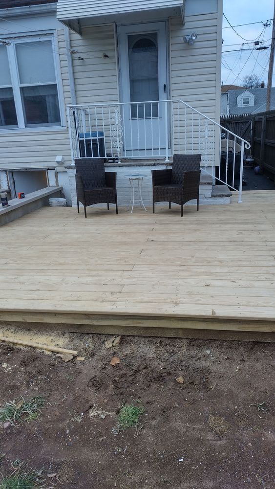A wooden deck with two chairs and a table in front of a house