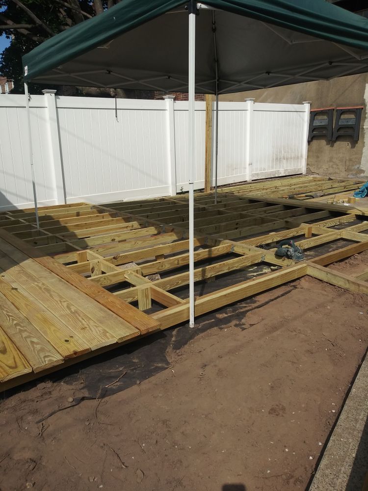 A wooden deck under a canopy with a white fence in the background