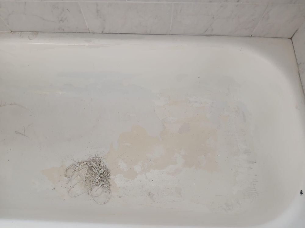 A white bathtub with a drain in the corner of it