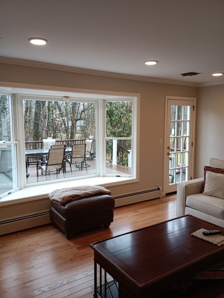 A living room with a couch, coffee table, ottoman and large window