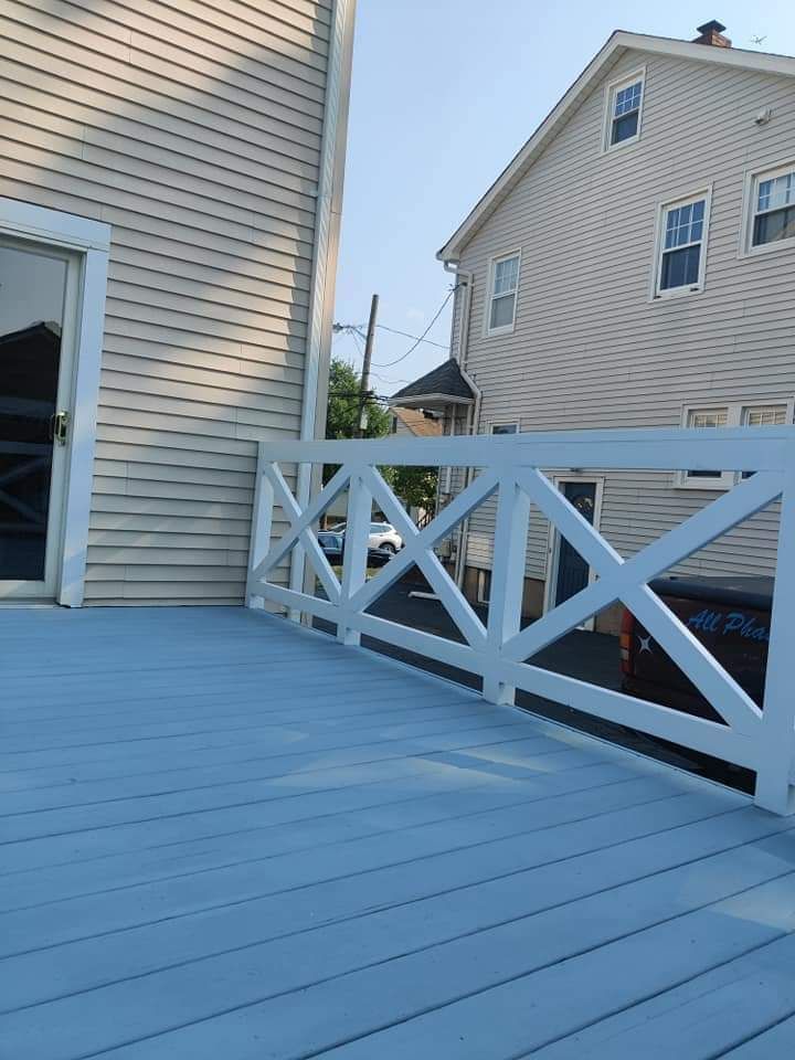 A blue deck with a white railing in front of a house