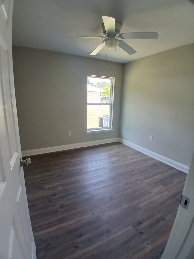 An empty bedroom with hardwood floors and a ceiling fan