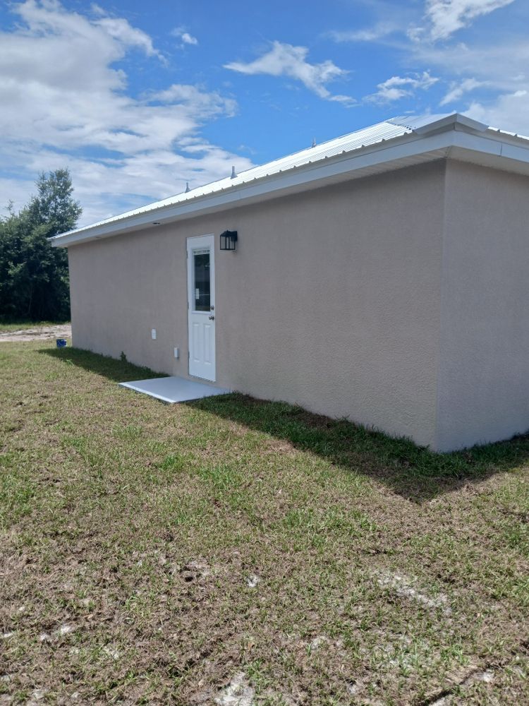 A small house with a white door is sitting in the middle of a grassy field