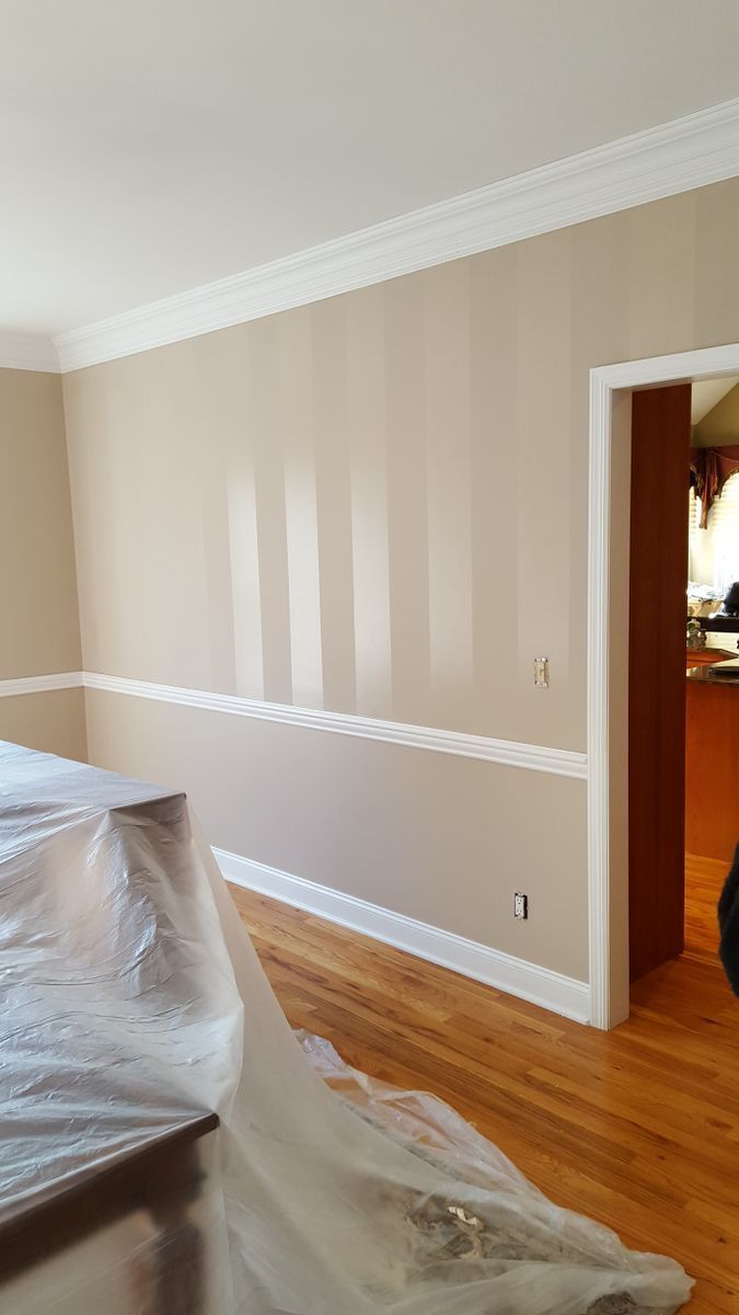 A living room with hardwood floors and beige walls is being painted
