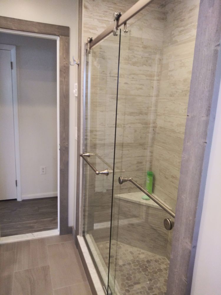 A bathroom with a sliding glass shower door and a bench