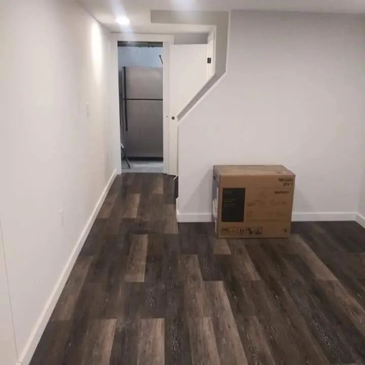A room with hardwood floors and a refrigerator in the background
