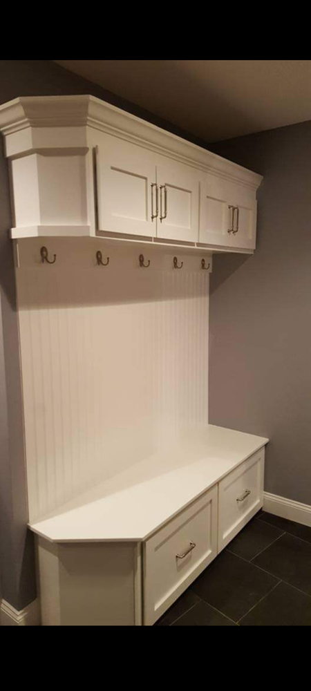 A white bench with drawers and hooks in a hallway