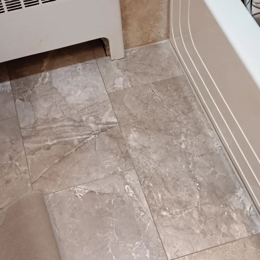 A tiled floor in a bathroom next to a bathtub