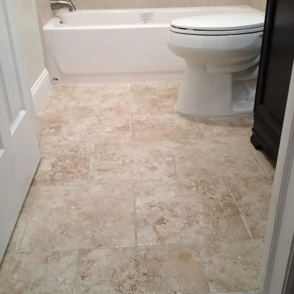 A bathroom with a toilet, bathtub and tile floor