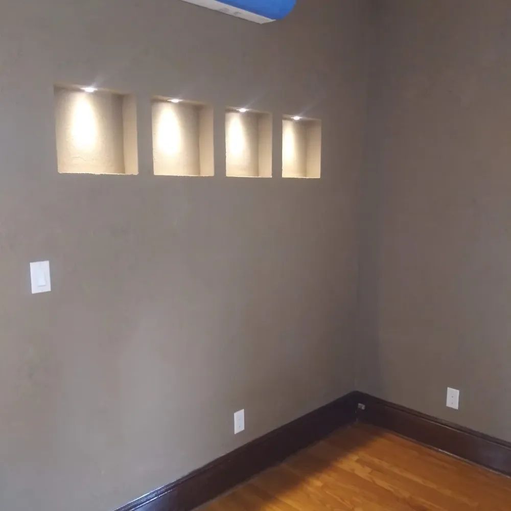 A room with a wooden floor and a row of niches on the wall.