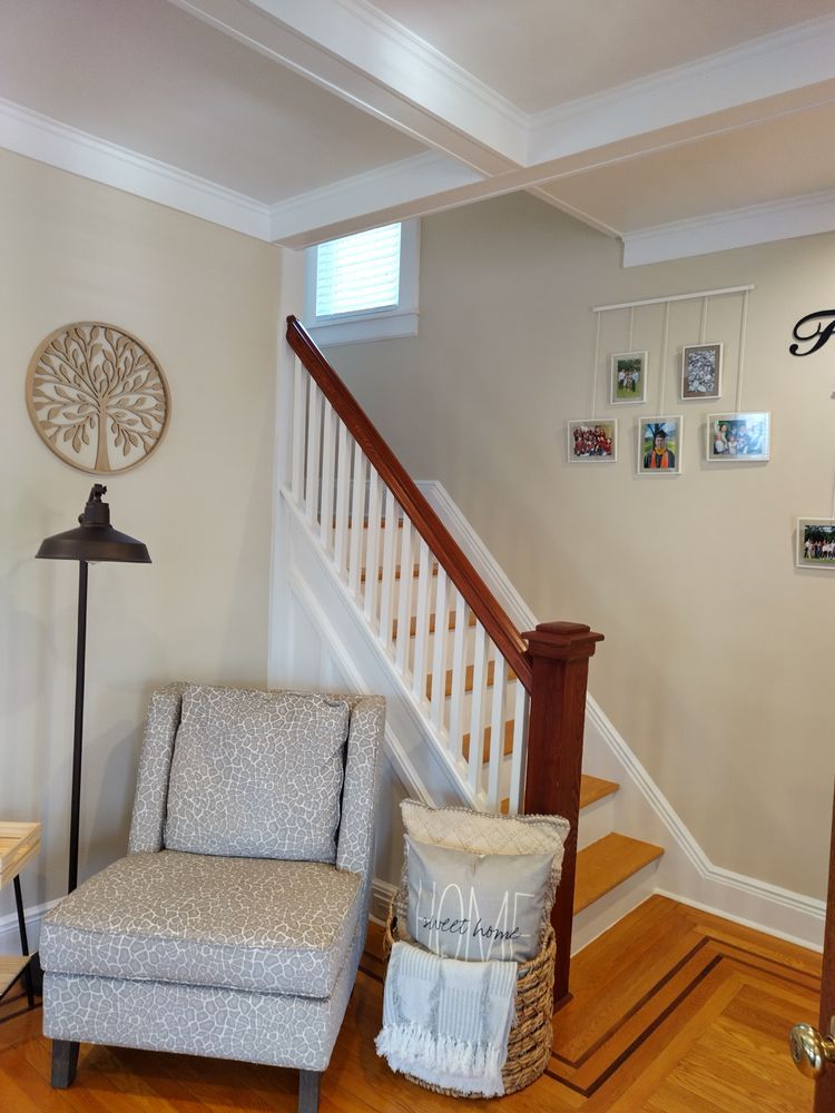A living room with a chair a lamp and stairs