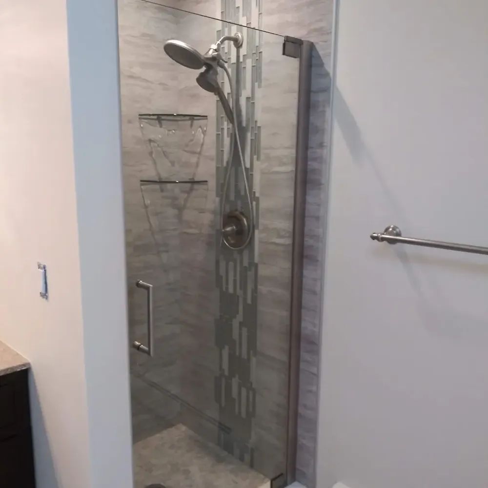 A bathroom with a walk in shower with a glass door and a shower head