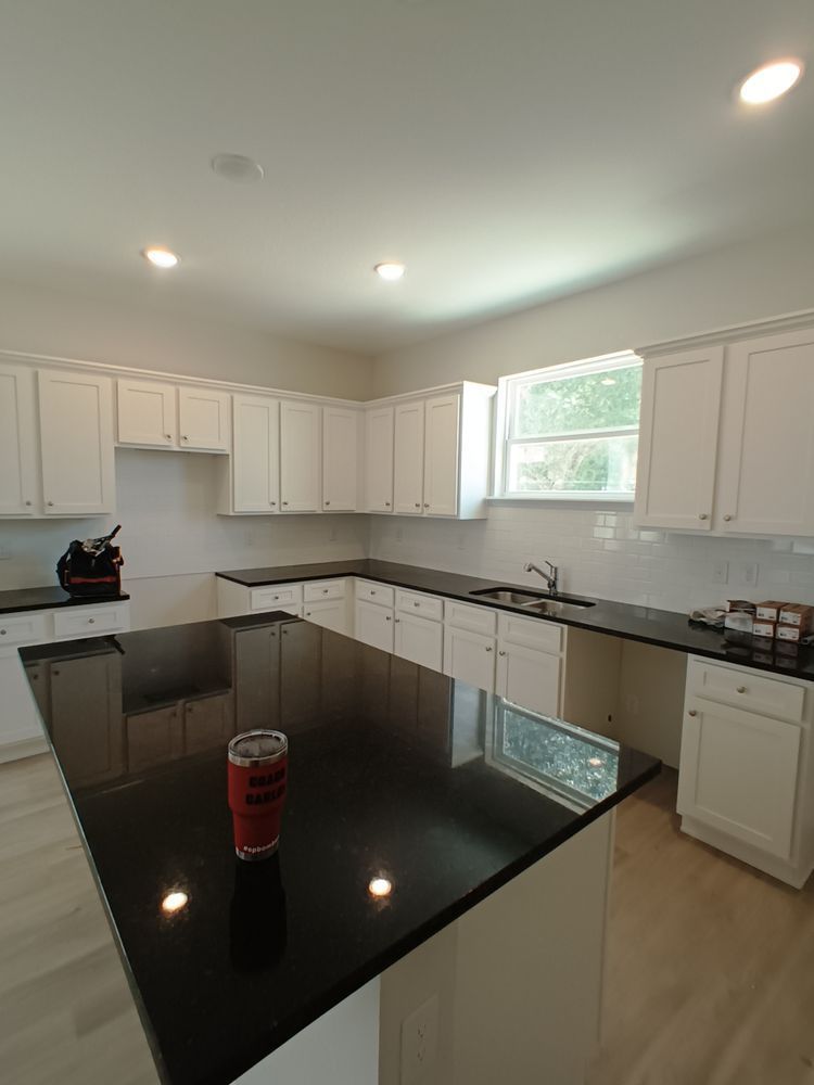 A kitchen with white cabinets and black counter tops and a can of soda on the counter.