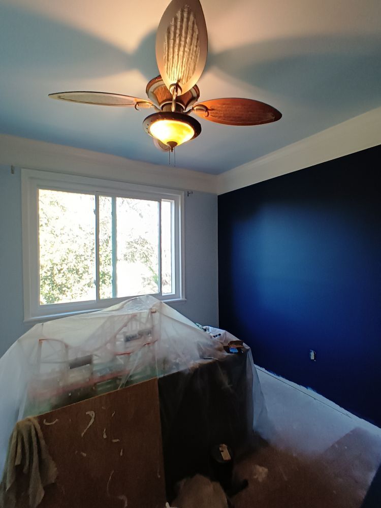 A bedroom with blue walls and a ceiling fan