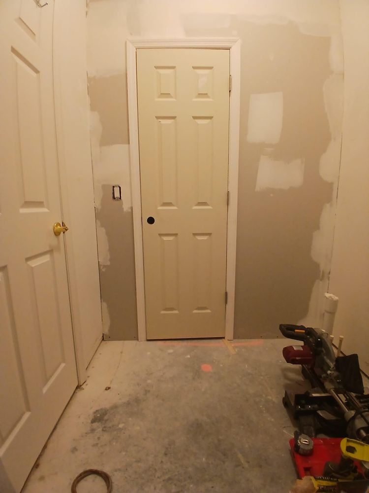 A hallway with a door and a bunch of tools on the floor