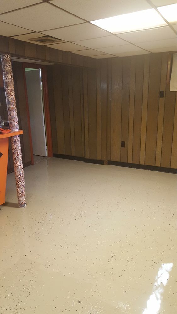 An empty room with wood paneling and a white floor