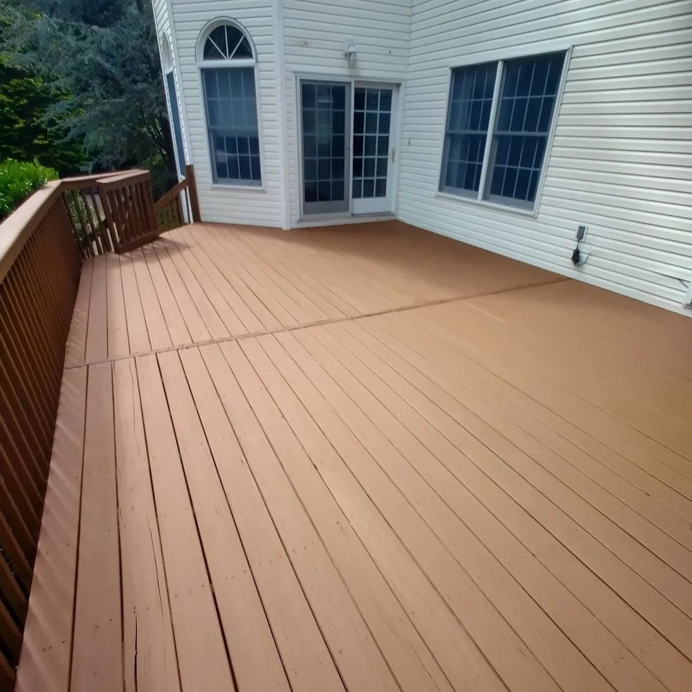 A large wooden deck with a white house in the background