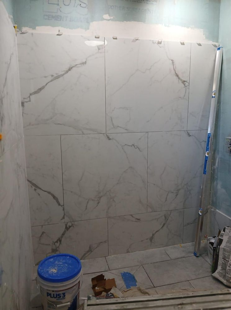 A bathroom with marble tiles being installed on the wall and floor.