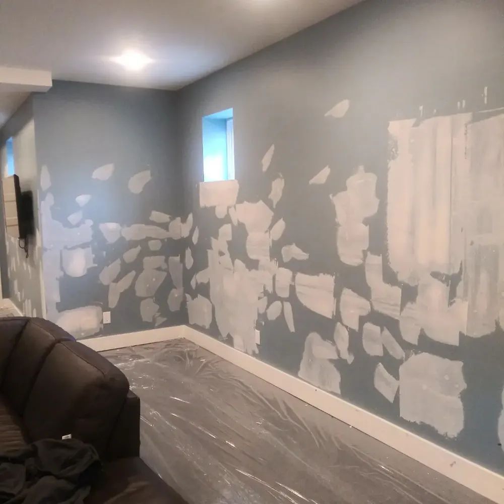 A living room with a couch and a wall that is being painted