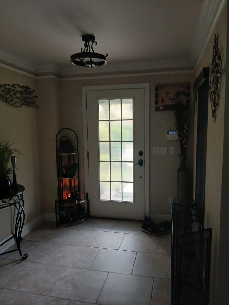 A hallway with a white door and a chandelier hanging from the ceiling