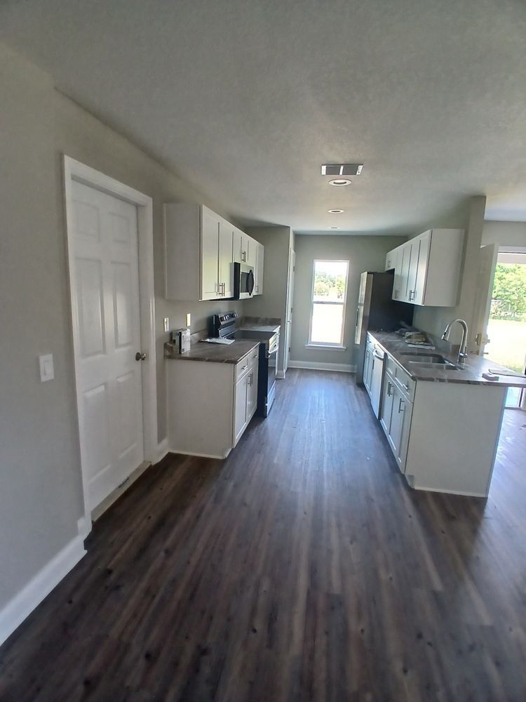 A kitchen in a house with hardwood floors and white cabinets
