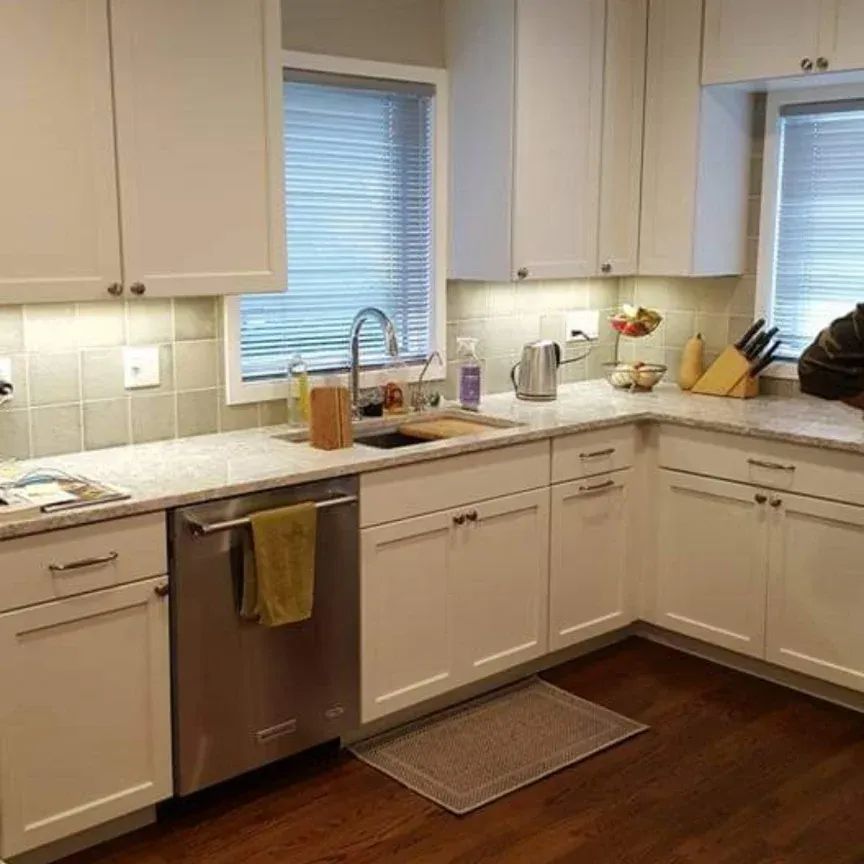 A kitchen with white cabinets, stainless steel appliances, a sink, and a window