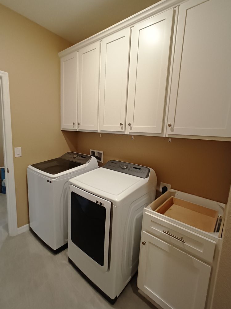 A laundry room with a washer and dryer and white cabinets