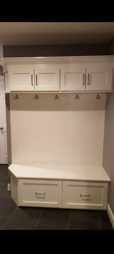 A white bench with drawers and hooks in a hallway
