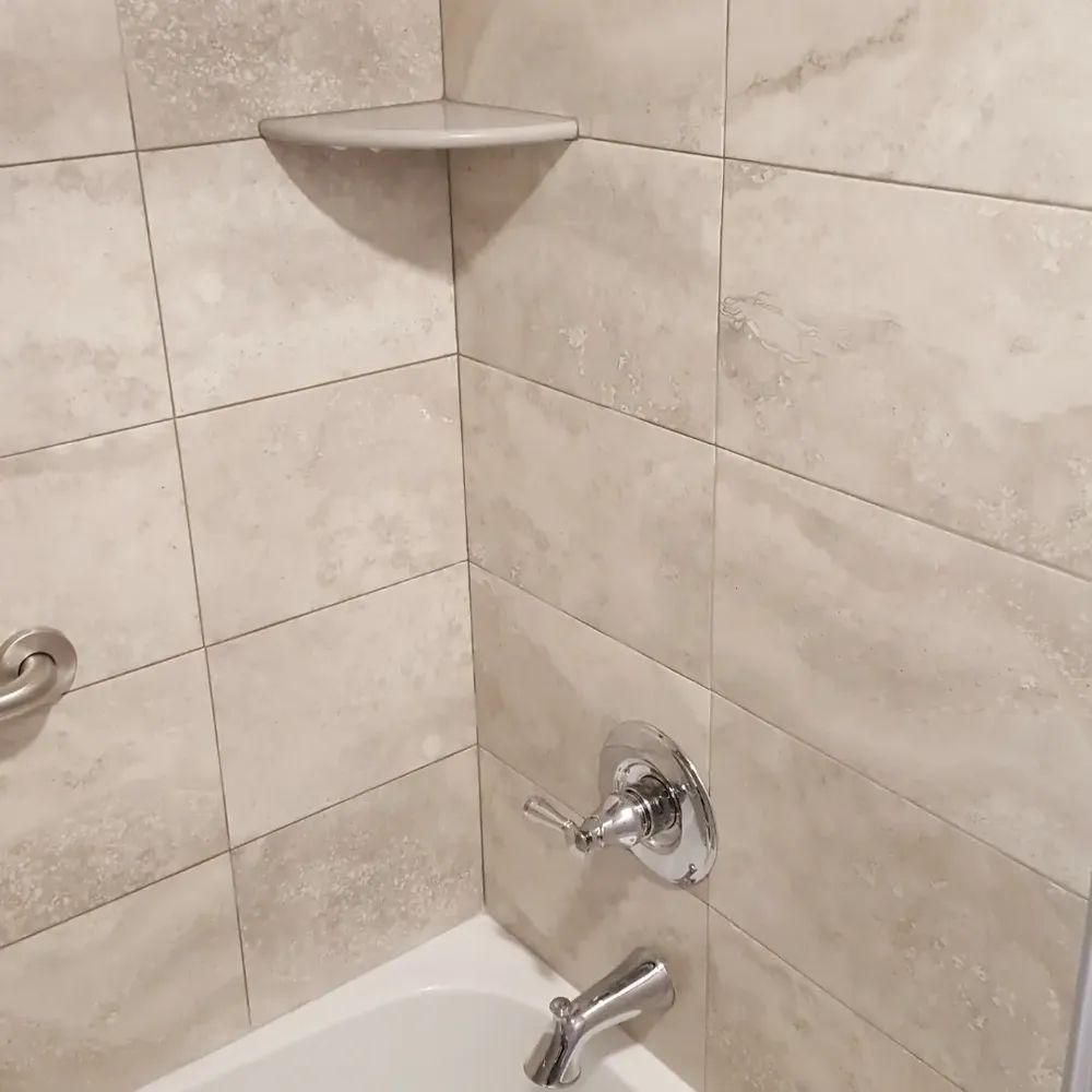 A bathroom with a bathtub and a shelf on the wall
