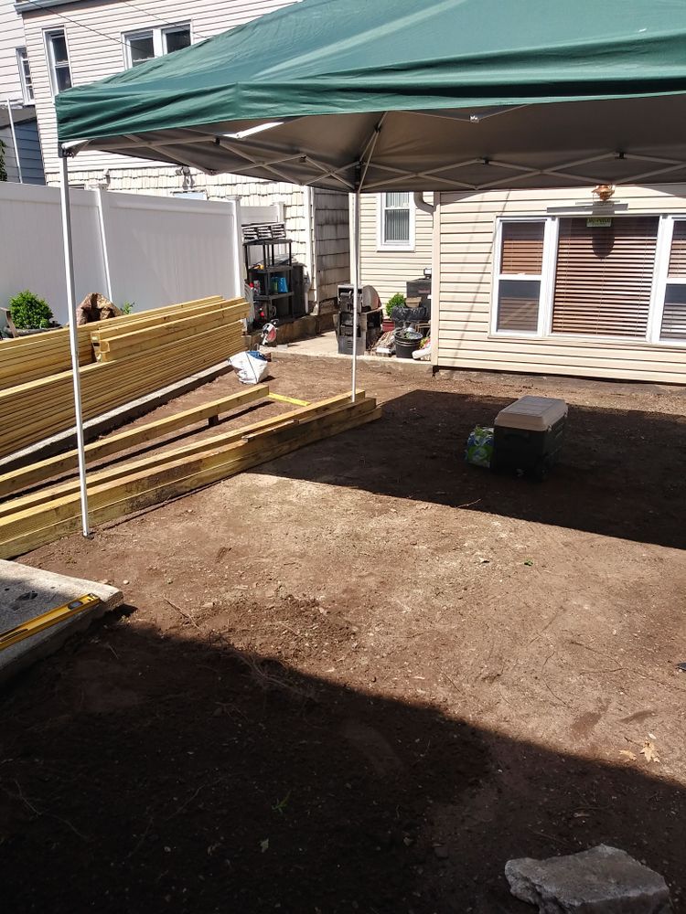 A backyard with a green canopy and wooden boards on the ground