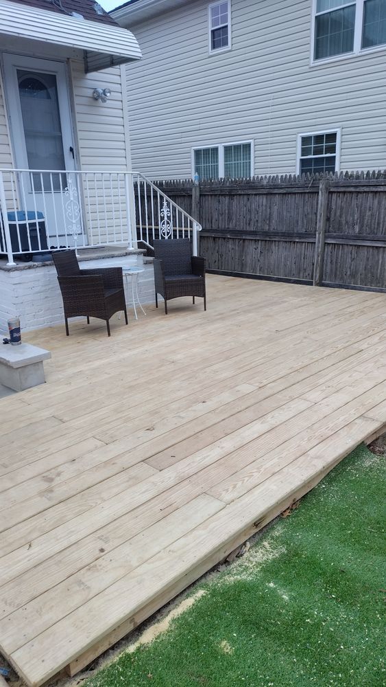 A wooden deck with chairs and a fire pit in front of a house