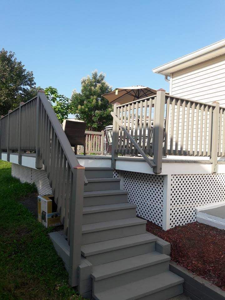 A deck with stairs leading up to it and a house in the background