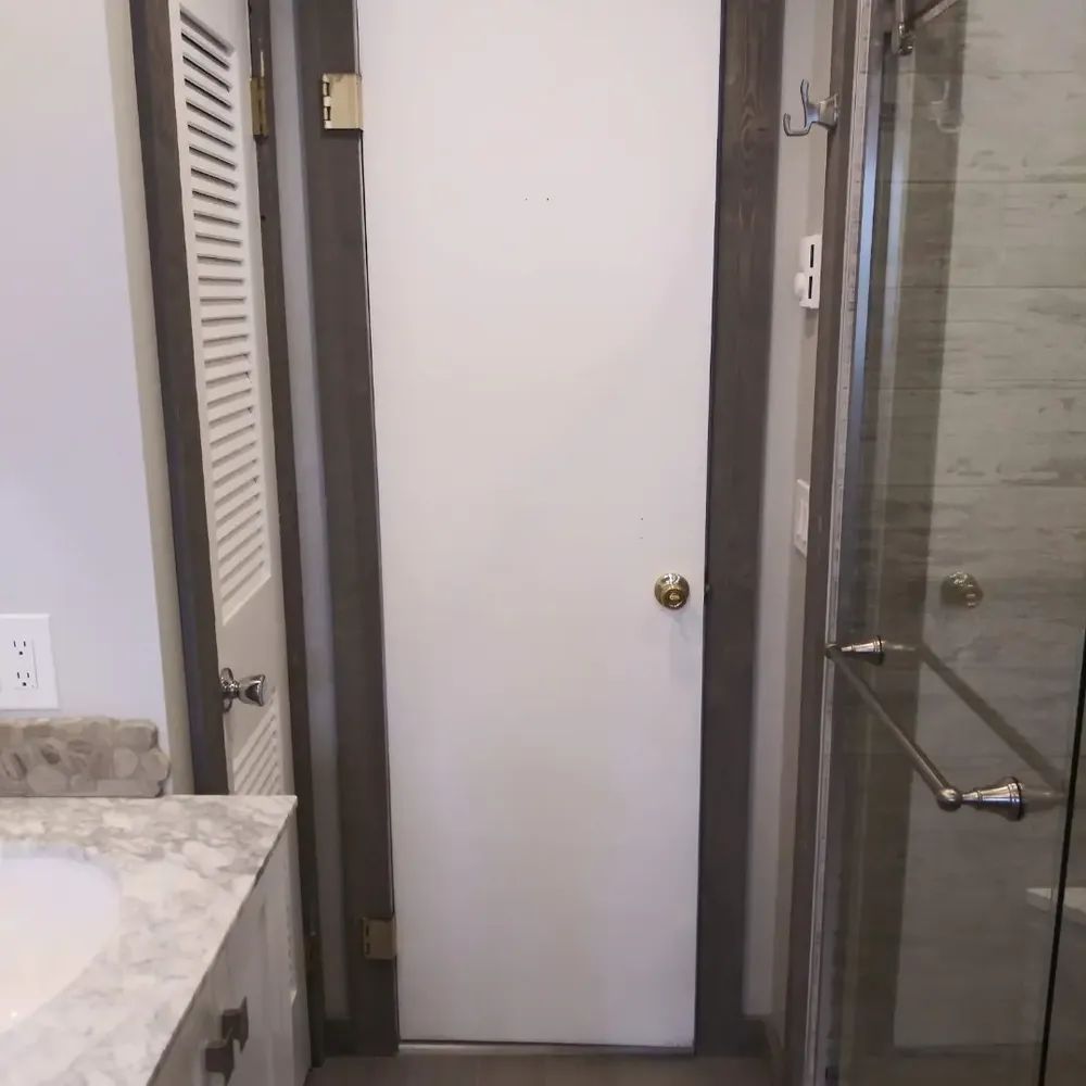 A bathroom with a white door and a glass shower door