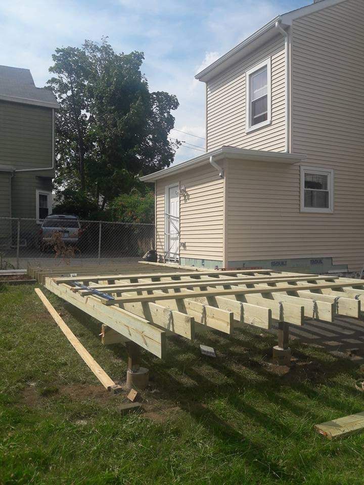 A wooden deck is being built in front of a house