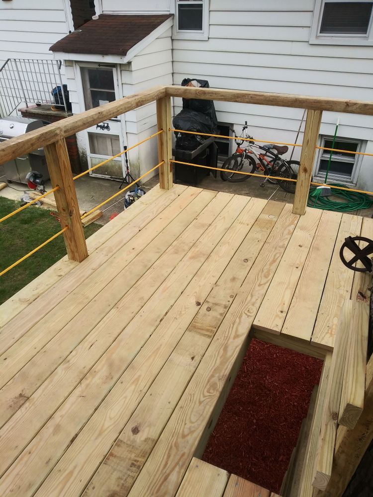 A wooden deck with a railing is being built in front of a house