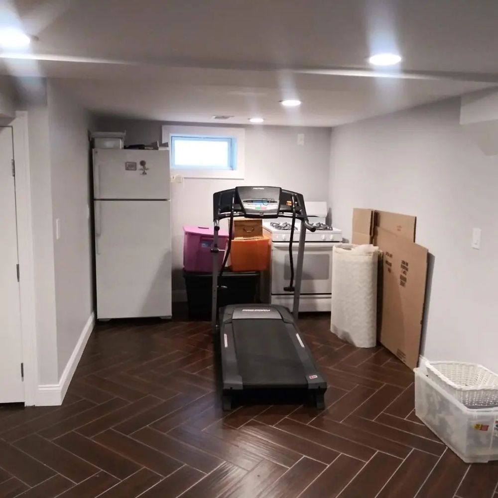 A treadmill is sitting in a basement next to a refrigerator