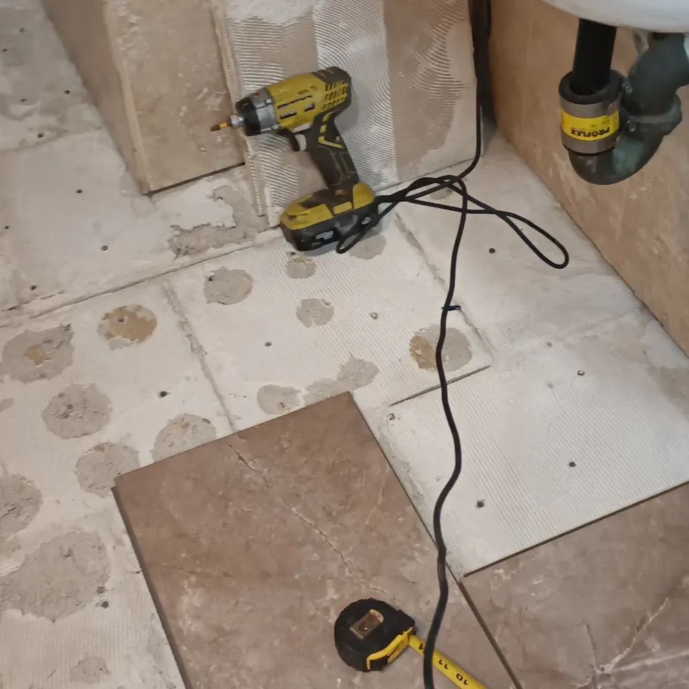 A drill is connected to a tape measure in a bathroom