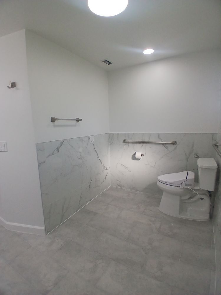 A bathroom with a toilet and a hand rail