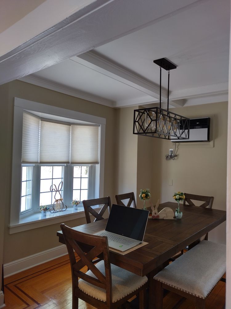 A dining room with a table and chairs and a laptop on it