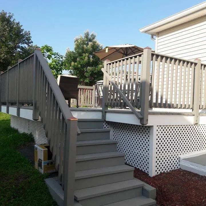 A deck with stairs leading up to it and a house in the background