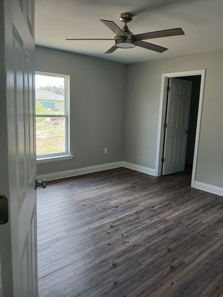 An empty bedroom with a ceiling fan and a window
