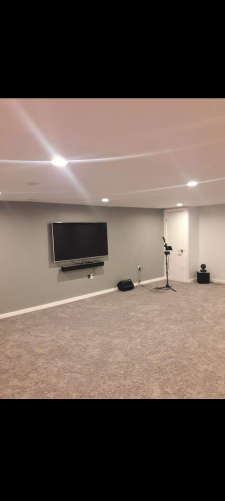 An empty basement with a flat screen tv on the wall