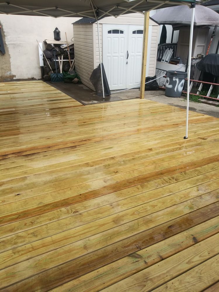 A wooden deck with a canopy and a shed in the background